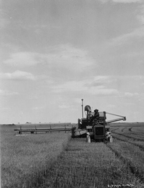 View from front of two men using a harvester-thresher in a field.