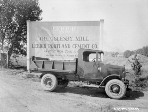 View of an International truck parked on the side of a road in front of a billboard. The billboard reads: "Lehigh Cement, The Oglesby Mill."