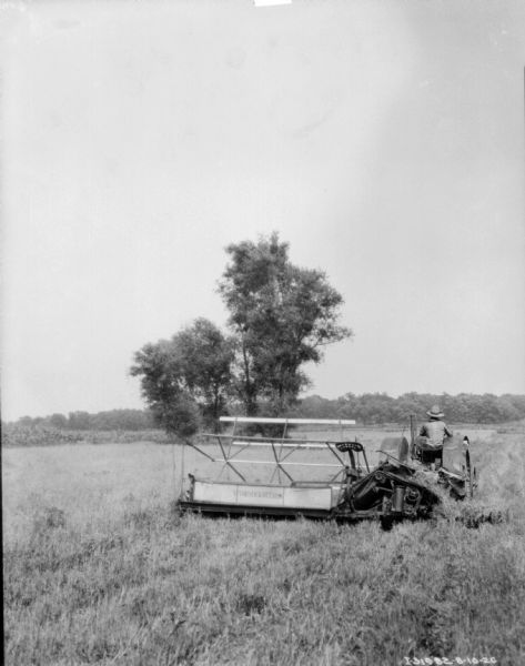 Rear view across field towards a tractor drawn binder in a field.