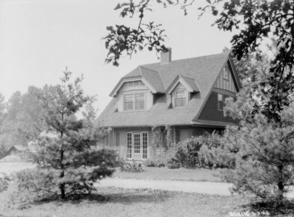 View across yard towards the home at the Katherine Legge Memorial. The greenhouse is in the background on the left, behind a tree in the foreground.