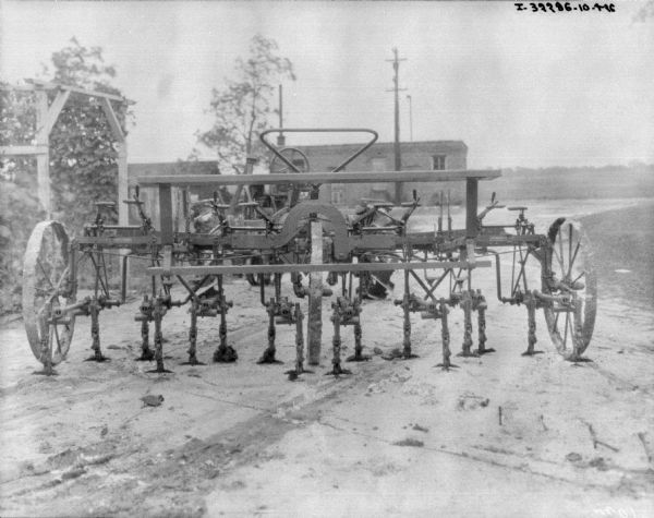 Cultivator set up on an unpaved road. Buildings are in the background.