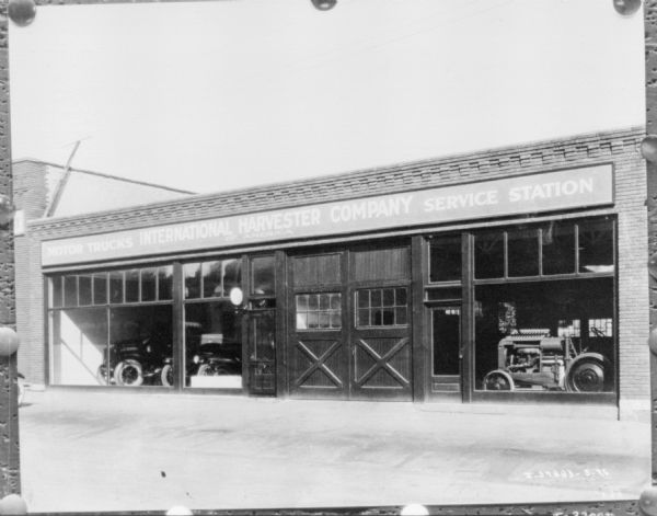 Exterior view of front of dealership. There are automobiles and a tractor on display behind the large windows of the storefront.