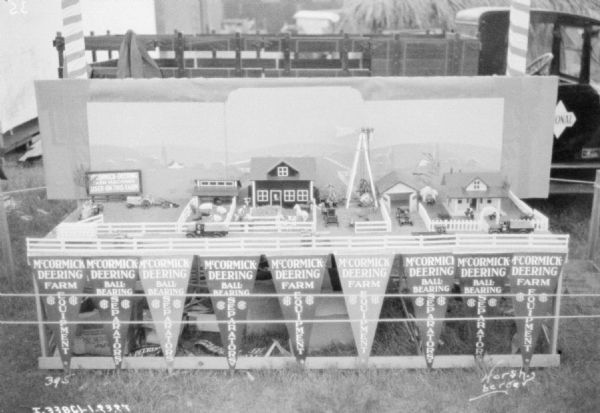 Miniature farm display with fences, tractor, water tower, and farm buildings. Pennants on the front of the display read: "McCormick-Deering Farm Equipment," and "Ball-Bearing Separators."