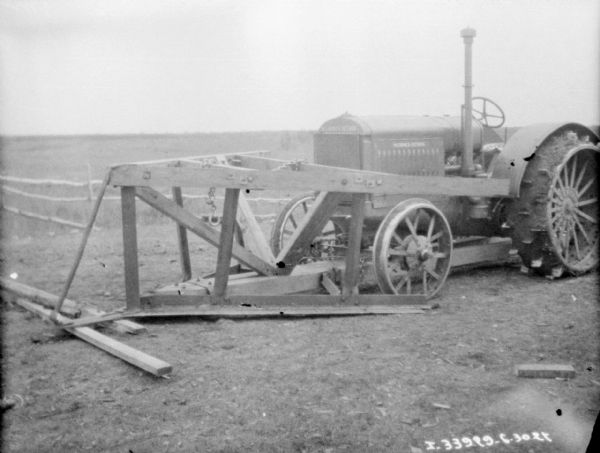A large metal and wood frame is attached to the front of a Titan 15-30 McCormick-Deering tractor for knocking down trees.