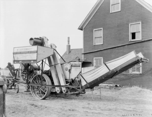 A harvester-thresher and shredder are parked in a farm yard.