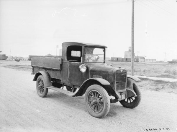 Three-quarter view from front right of a man in the driver's seat of a grain delivery truck.