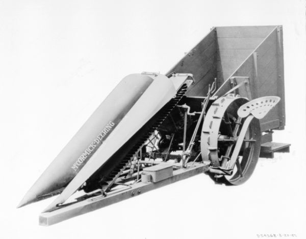 Three-quarter side view of cotton picker. There is a tractor seat on the side of the machine near the wheel.