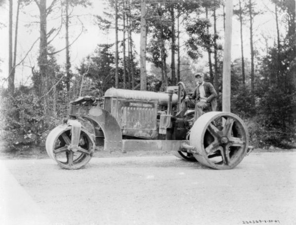 View of a man sitting on a McCormick-Deering tractor fitted with road rollers.