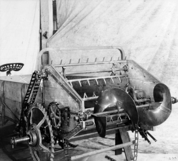 Rear view of a manure spreader set up in front of a backdrop.