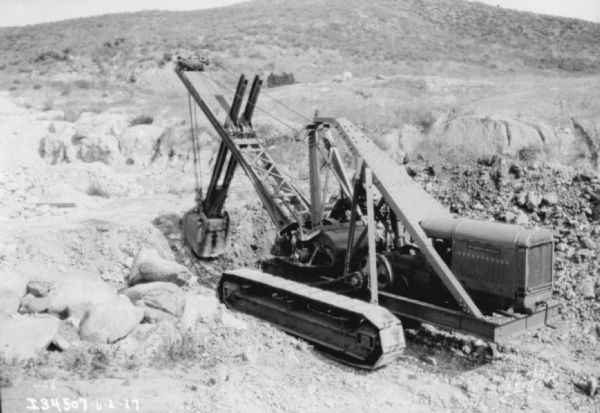 Slightly elevated view of a man operating an earthmover. A hill is in the background.
