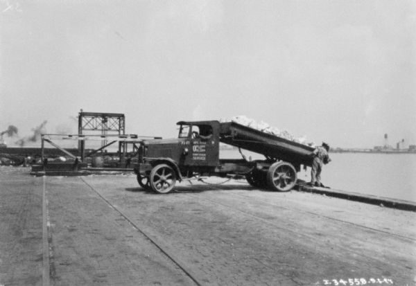 Man Using Dump Truck to Unload Material into Water Photogr