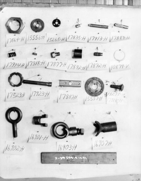 Parts are displayed on a wall, with their serial numbers attached below. At the bottom of the display is a piece of board on which is written: "12 IN."