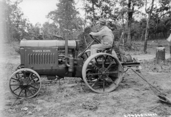 Man using a McCormick-Deering tractor among trees at the C.W. O'Halloran Co.