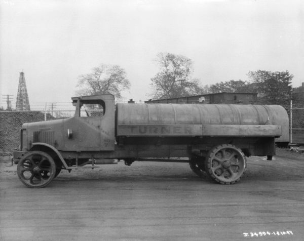 Driver's side view of a Bob Armistead oil delivery truck parked outdoors. Behind the truck is a railroad car on railroad tracks.