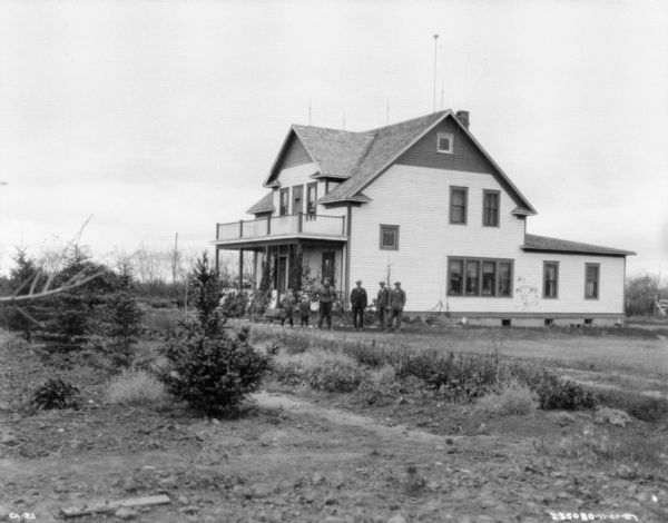 Family standing in front of a farmhouse on a farm.