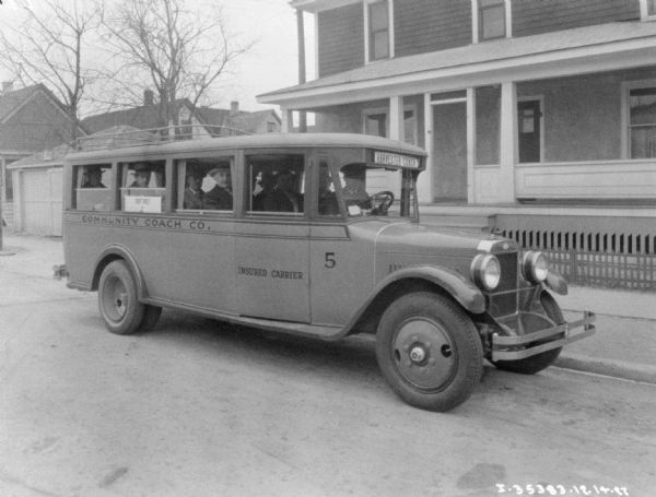 A group of men are sitting inside a Harvester Coach. The sign on the side of the passenger side door reads: "Insured Carrier."
