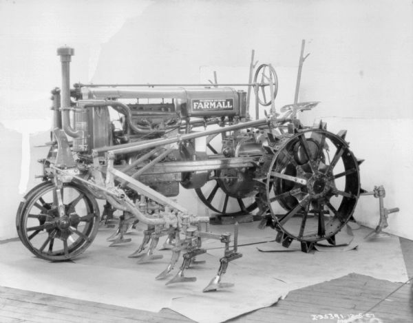 Left side view of a McCormick-Deering Farmall tractor parked indoors. There is a white backdrop behind the tractor.