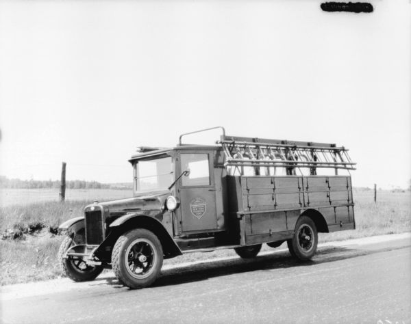 View across road towards a delivery truck parked along the side of the road. The sign painted on the driver's side door reads: "Toll Service Everywhere, Northern New York Telephone Corp."