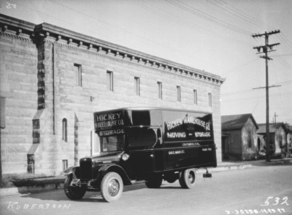 View across street towards a delivery truck. The sign painted on the side of the truck reads: "Hickey Warehouse Co. Moving – Storage."