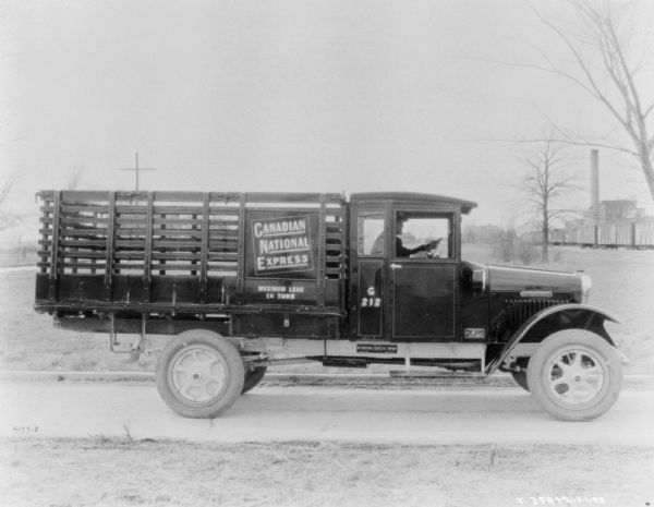 Right side view of a truck with a stake body and a sign that reads: "Canadian National Express."