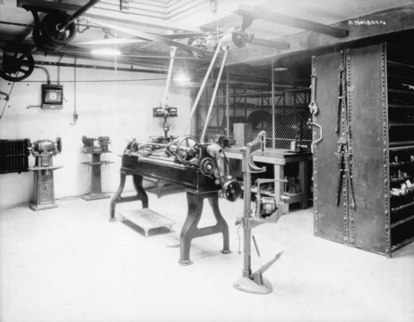 Interior view of a repair room. Machinery on the floor is belt-driven from machinery on the ceiling.