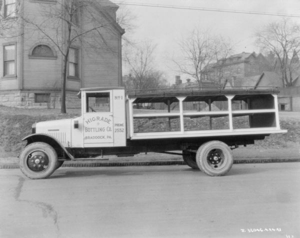 View across street towards a truck parked along the curb. The sign painted on the driver's side door reads: "Higrade Bottling Co."