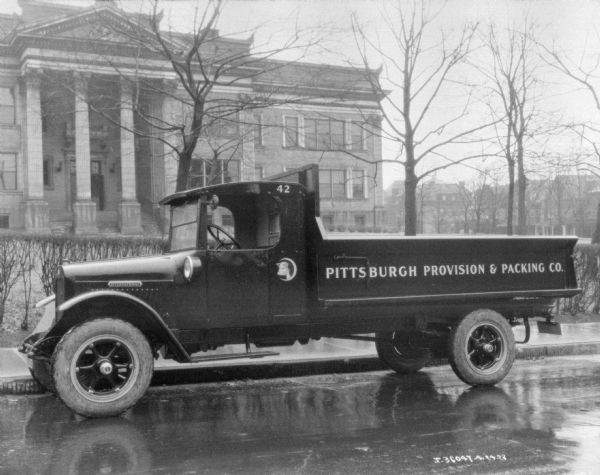 View across street towards a truck parked along the curb. The sign painted on the side of the truck bed reads: "Pittsburgh Provision & Packing Co."