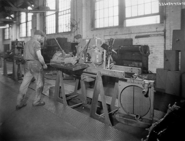 Two men are working on an assembly line for Farmall tractors.