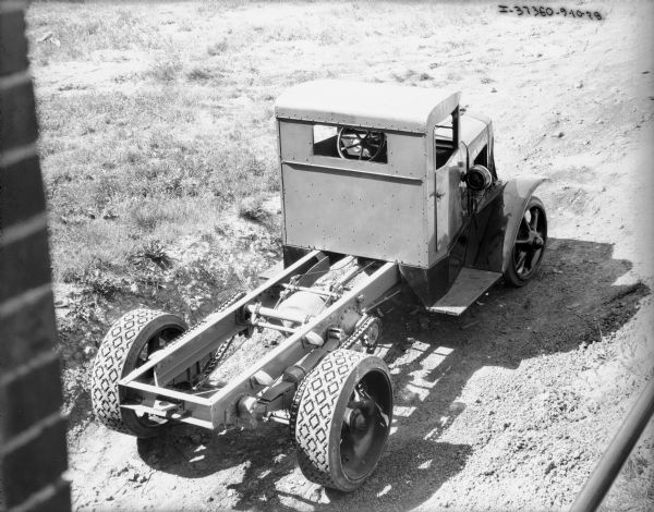Three-quarter elevated view from right rear of an International truck with cab and an exposed chassis parked outdoors. A brick wall is on the far left.