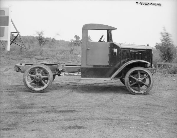 Right side profile view of a truck with a cab and an exposed chassis parked outdoors.