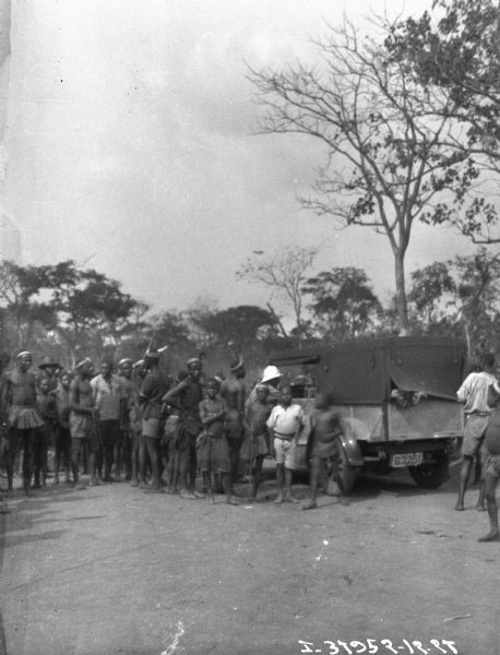 Large group of African villagers standing near an International truck.