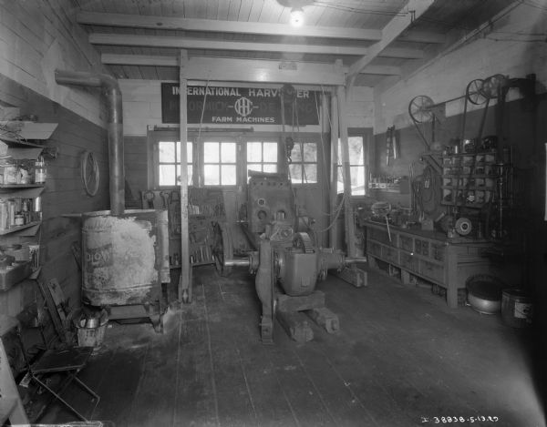 Interior view of a repair shop at a dealership. A sign on the wall reads: "International Harvester McCormick-Deering Farm Machines."