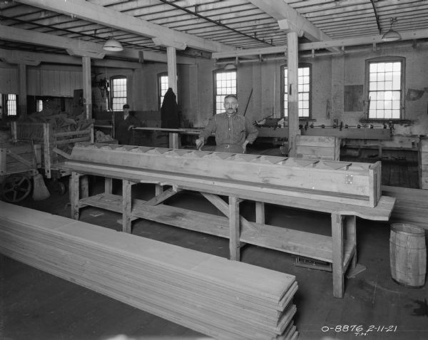 Two men are standing in a room in a factory. Sequence showing the assembly of disk harrows, attachments and seeders.