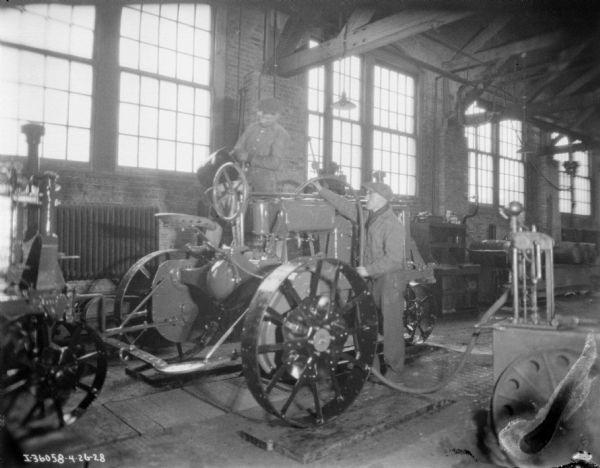 Two Men Assembling Parts For Farmall Tractor 