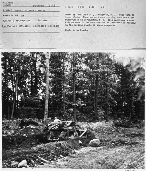 View towards a man driving a TD-18 crawler tractor.
Subject: "TD-18A — Land Clearing." Where Taken: "NE." Information with photograph reads: "Owned by John Ochs Co., Livington, N.J. Used with BE dozer blade. Shown at work constructing road for a new subdivision in Livington, N.J. This machinery is usually at work in the construction of factories or working in the various plants of those companies. Photo by L. Bouche."