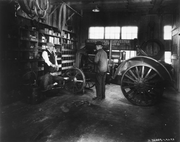 Three men are in a dealership near a tractor.