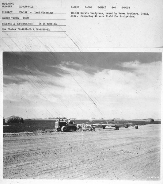 View across field towards a man driving a TD-18A. Subject: "TD-18A — Land Clearing." Where Taken: "MidW." Information with photograph reads: "TD-18A Marvin Landplane, owned by Brown Brothers, Cozad, Nebr. Preparing 40 acre field for irrigation."