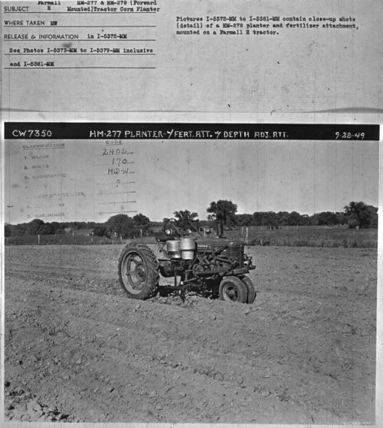 Three-quarter view from front right of a Farmall H in field. Subject: "Farmall H. HM-277 & HM-278 (Forward Mounted) Tractor Corn Planter." Where Taken: "MW." Information with photograph reads: "Pictures I-5372-MM to I-5381-MM contain close-up shots (detail) of a HM-278 planter and fertilizer attachment, mounted on a Farmall H tractor."