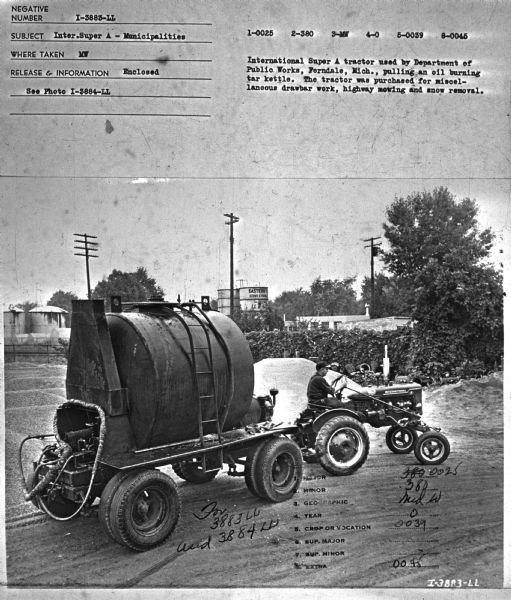 Right side view of a man driving a tractor pulling an oil burning tar kettle on a trailer. Subject: "Inter. Super A — Municipalities." Where Taken: "MW." Information with photograph reads: "International Super A tractor used by Department of Public Works, Ferndale, Mich., pulling an oil burning tar kettle. The tractor was purchased for miscellaneous drawbar work, highway mowing and snow removal."