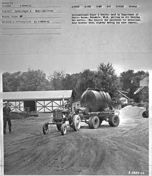 Front view of a man driving a tractor pulling an oil burning tar kettle on a trailer. Another man is standing nearby on the left. Subject: "Inter. Super A — Municipalities." Where Taken: "MW." Information with photograph reads: "International Super A tractor used by Department of Public Works, Ferndale, Mich., pulling an oil burning tar kettle. The tractor was purchased for miscellaneous drawbar work, highway mowing and snow removal."