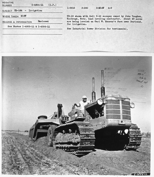 Three-quarter view from front left of a man driving a TD-18A in a field. Subject: "TD-18A — Irrigation." Where Taken: "MidW." Information with photograph reads: "TD-18 shown with Heil C-10 scraper owned by John Vaughan, Holdrege, Nebr. land leveling contractor. About 40 acres are being leveled on Carl W. Hanson's farm near Bertrand, for irrigation."