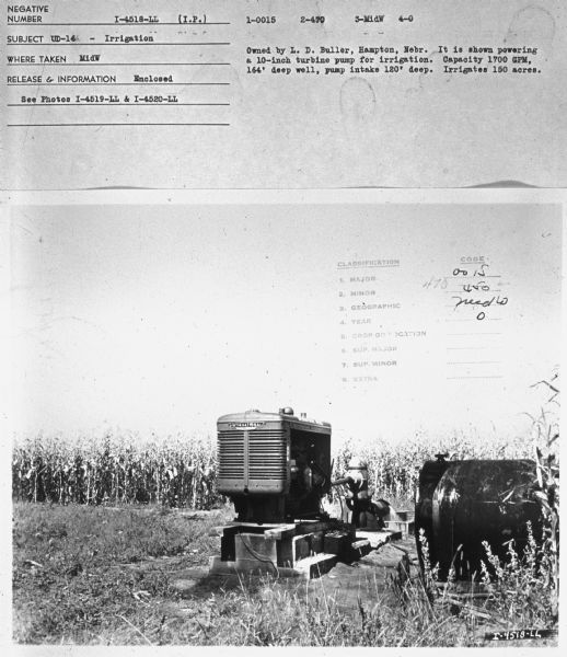 A UD-16 sitting outdoors, with a storage tank on the right. There is a cornfield in the background. Subject: "UD-16 — Irrigation." Where Taken: "MidW." Information with photograph reads: "Owned by L.D. Buller, Hampton, Nebr. It is shown powering a 10-inch turbine pump for irrigation. Capacity 1700 GPM, 164' deep well, pump intake 120' deep. Irrigates 150 acres."