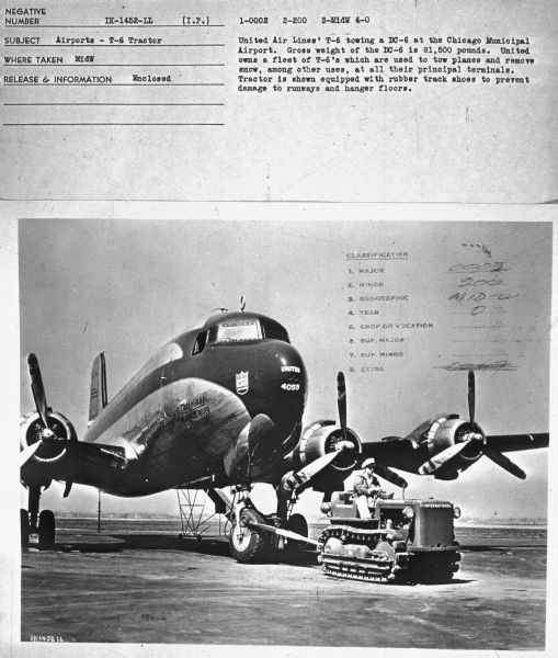 Subject: "Airports — T-6 Tractor." Where Taken: "MidW." Information with photograph reads: "United Air Lines' T-6 towing a DC-6 at the Chicago Municipal Airport. Gross weight of the DC-6 is 81,500 pounds. United owns a fleet of T-6's which are used to tow planes and remove snow, among other uses, at all their principal terminals. Tractor is shown equipped with rubber track shoes to prevent damage to runways and hanger[sic] floors."