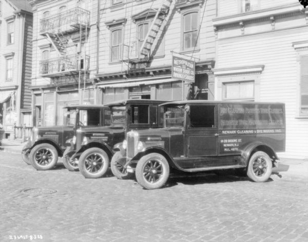 Fleet of laundry trucks parked in front of buildings.
