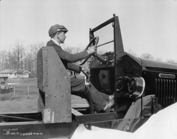Close-up of a man driving a truck. The cab is exposed, and the man is sitting on a wooden seat.