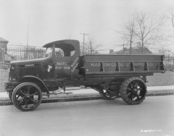 View across street towards the driver's side of a delivery truck parked along a curb. The sign painted on the truck reads: "Marion Coal & Supply Co."