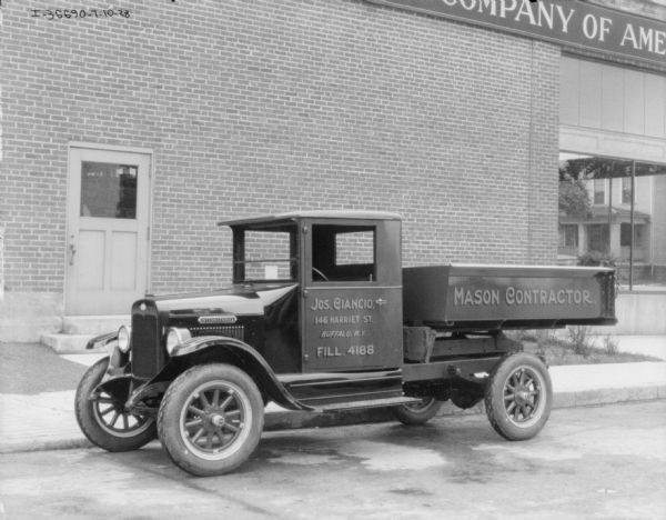 View towards the driver's side of a delivery truck parked outdoors in front of a brick building. The sign painted on the side of the truck reads: "Jos. Ciancio." and "Mason Contractor."