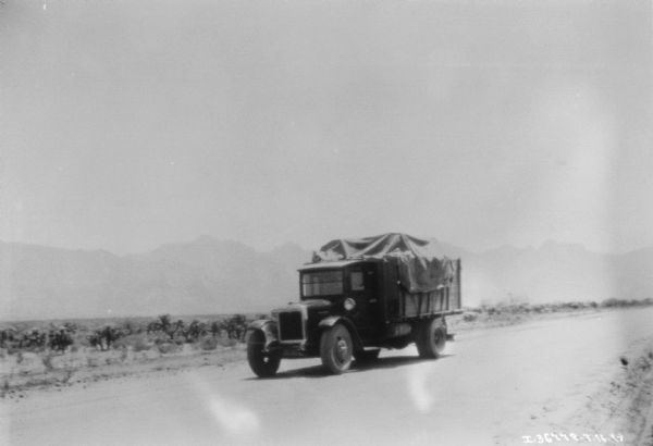 View of a truck on a road. Mountains are in the background.