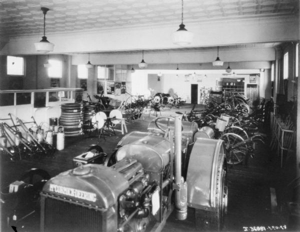 View of interior of dealership, with tractors, agricultural implements, and other supplies on display.
