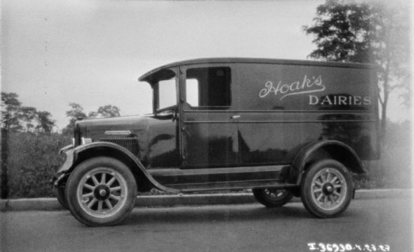View towards the driver's side of a delivery truck parked along a curb. The sign painted on the side reads: "Hoak's Dairies."